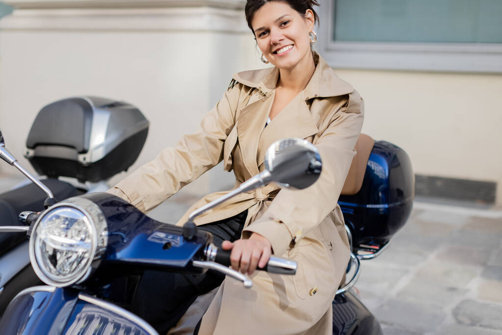 mulher alegre em casaco de trincheira bege em scooter  - Foto, Imagem