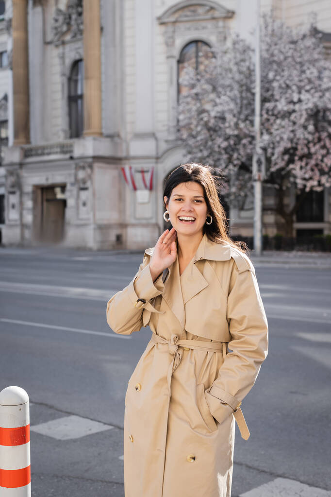 happy woman in elegant coat smiling on street in vienna  - Photo, Image