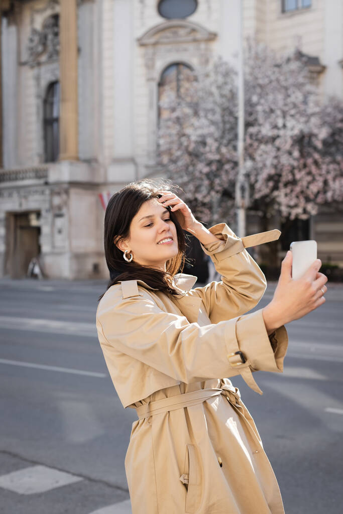 cheerful woman in stylish coat taking selfie on smartphone in vienna - Photo, Image