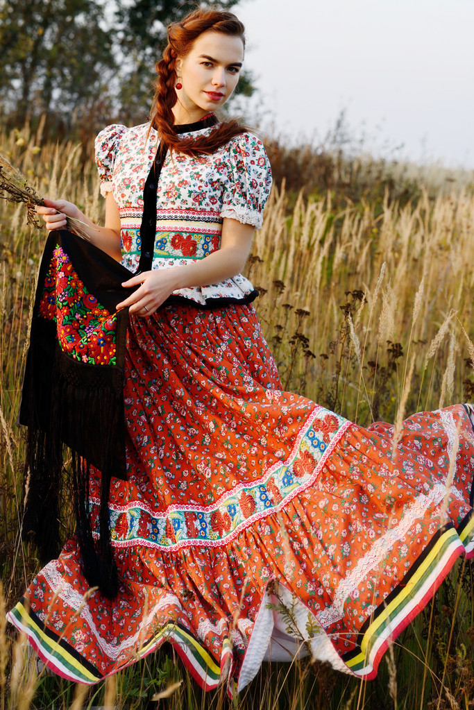Jonge boer vrouw, gekleed in Hongaarse nationale kostuum, die zich voordeed op aard achtergrond - Foto, afbeelding