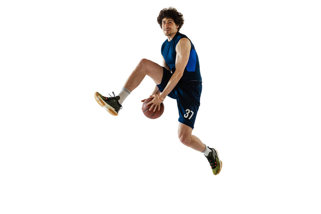 Mladý svalnatý basketbalista v akci, pohyb izolovaný na bílém pozadí. Koncepce sportu, pohybu, energie a dynamického, zdravého životního stylu. - Fotografie, Obrázek