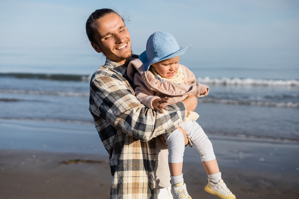 Feliz papá sosteniendo niña cerca borrosa mar adriático en Italia  - Foto, imagen