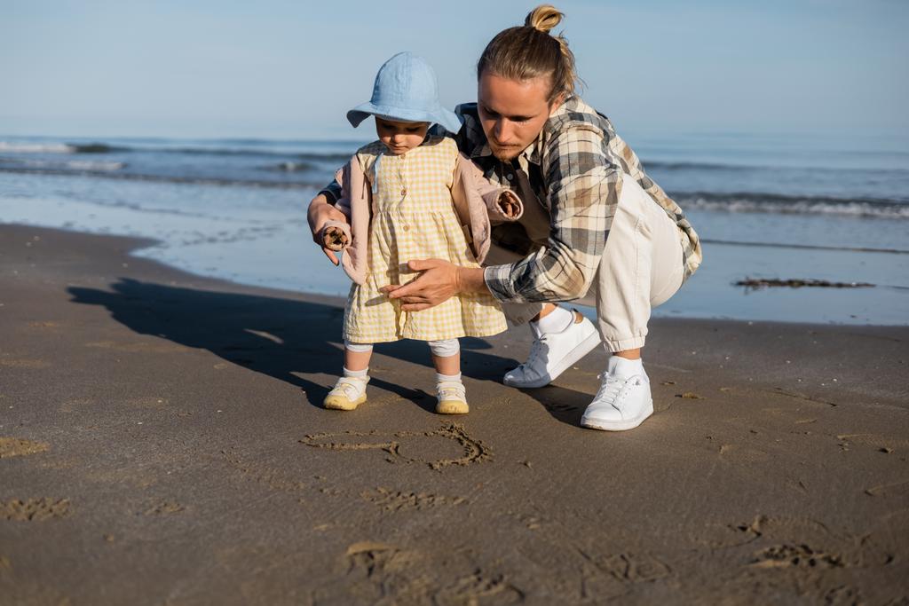 Parent and child looking at heart sign on beach in Treviso - Photo, Image