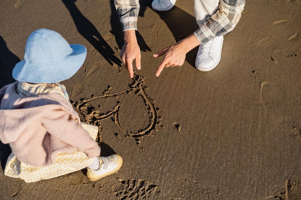 Férfi mutató szív jel homok közelében kislány a strandon  - Fotó, kép