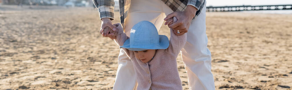 Мужчина держит за руки ребенка на пляже, баннер  - Фото, изображение
