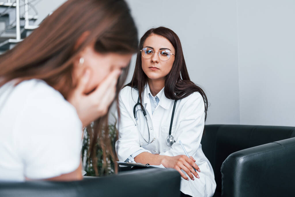 Mädchen haben einen Nervenzusammenbruch und weinen. Junge Frau besucht Ärztin in moderner Klinik. - Foto, Bild