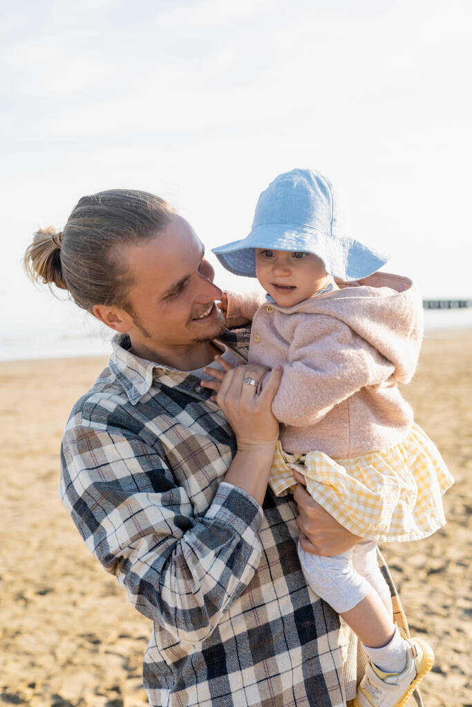 Тато з довгим волоссям тримає дитину на пляжі в Тревізо. - Фото, зображення