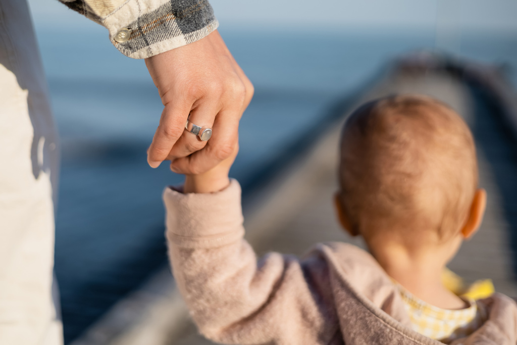Back view of father holding hand of blurred toddler daughter on pier - Photo, Image