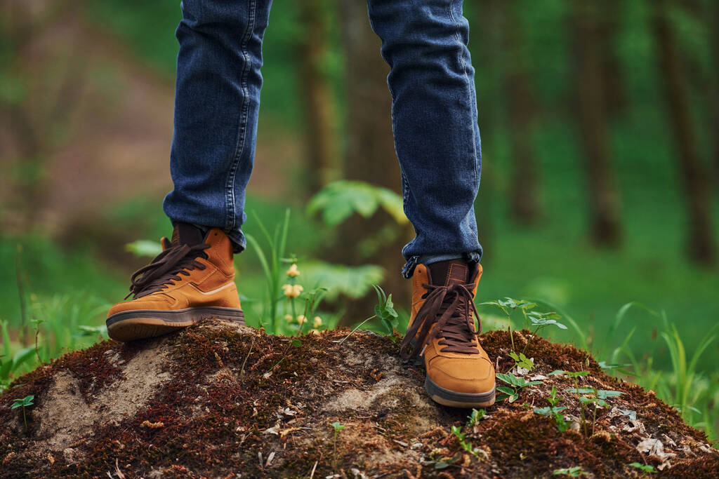 Vue rapprochée des jambes de l'homme sur le rocher dans la forêt. Voyageur faire une promenade. - Photo, image