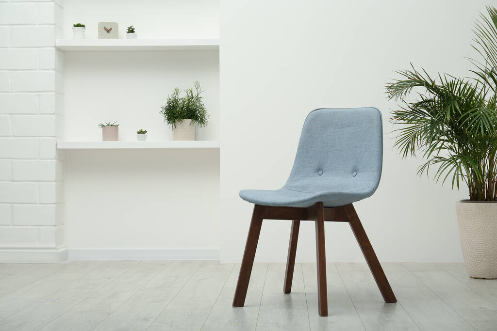Stijlvolle comfortabele grijze stoel en mooie kamerplant in lichte kamer. Ruimte voor tekst - Foto, afbeelding