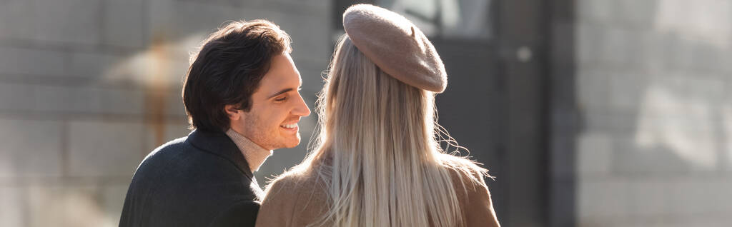 mujer rubia en boina cerca de hombre joven y feliz al aire libre, pancarta - Foto, Imagen