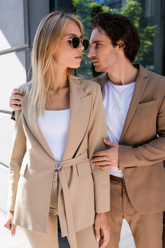 brunette man embracing stylish woman in sunglasses on urban street - Photo, Image