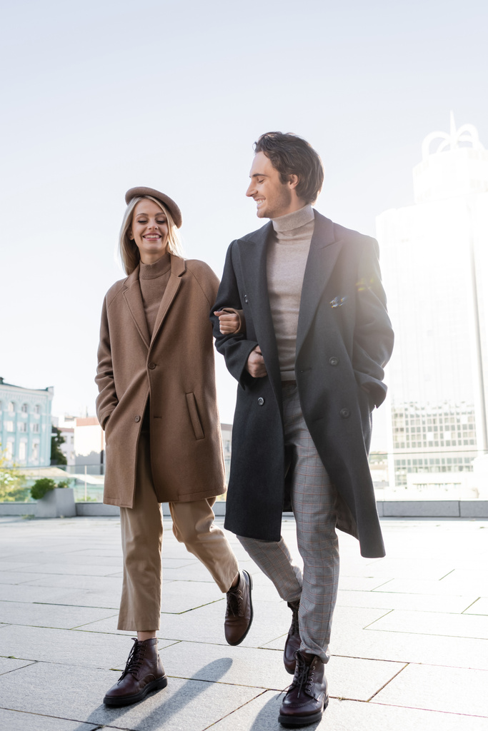 longueur totale de jeune couple en manteaux et bottes en cuir marchant en ville - Photo, image