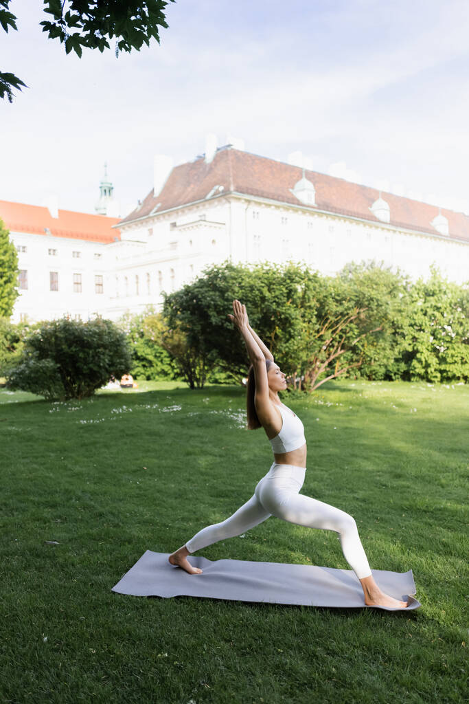 вид збоку спортивна жінка практикує позу півмісяця на йога мат в міському парку
 - Фото, зображення
