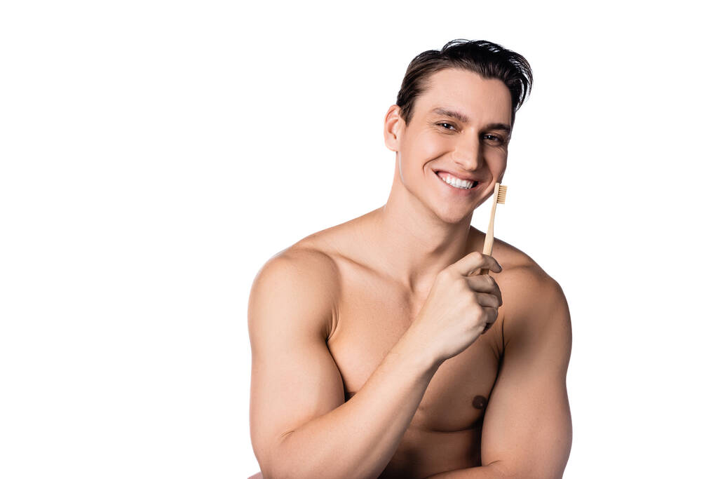 veselý muž bez košile se zubním kartáčkem při pohledu na kameru izolované na bílém - Fotografie, Obrázek