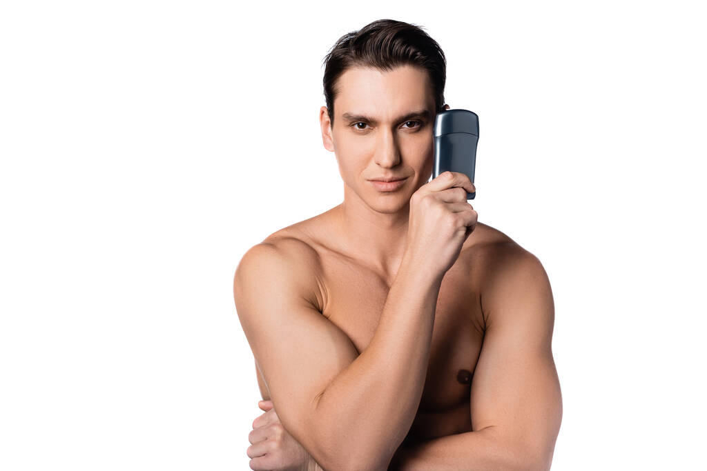positieve shirtloze man houdt anti-transpirant en kijken naar camera geïsoleerd op wit - Foto, afbeelding