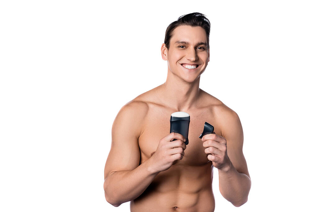 usmívající se muž se svalnatým trupem drží suchý deodorant izolovaný na bílém - Fotografie, Obrázek