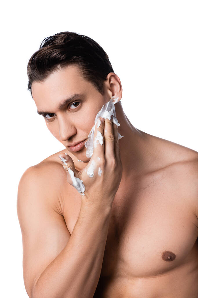 hombre con el pecho desnudo aplicando espuma de afeitar y mirando a la cámara aislada en blanco - Foto, imagen