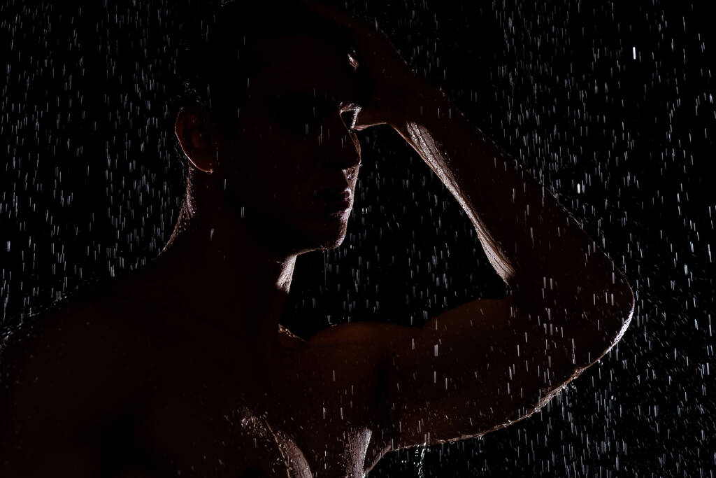 Silhouette des Menschen unter fallenden Wassertropfen auf schwarzem Hintergrund - Foto, Bild