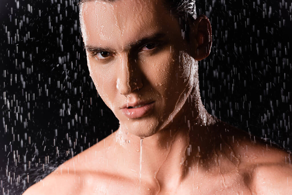 portré férfi csupasz vállak nézi kamera alatt zuhany fekete háttér - Fotó, kép
