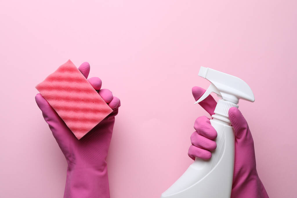 Frau in Gummihandschuhen mit Schwamm und Waschmittel auf rosa Hintergrund, Ansicht von oben - Foto, Bild