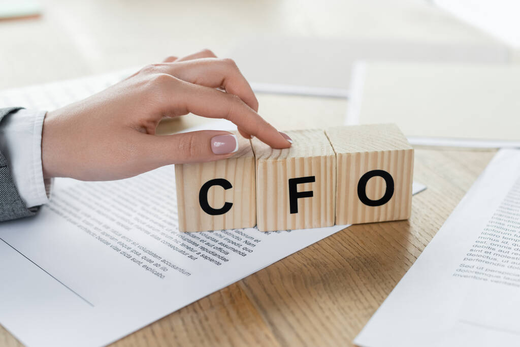 cropped view of businesswoman pointing at cubes with cfo lettering near documents - Photo, Image