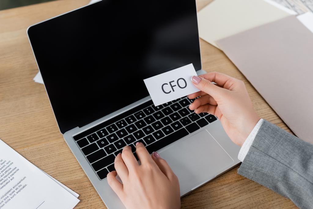 cropped view of woman holding paper with cfo lettering and using laptop  - Photo, Image