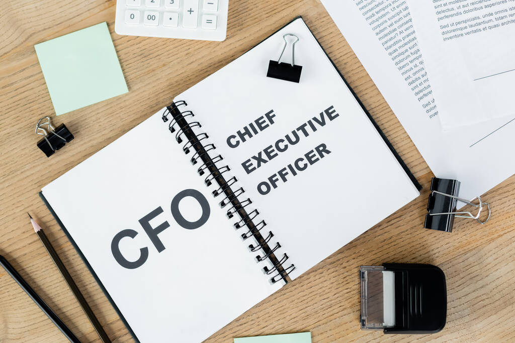 top view of notebook with cfo and chief executive officer lettering near documents and stationery  - Photo, Image