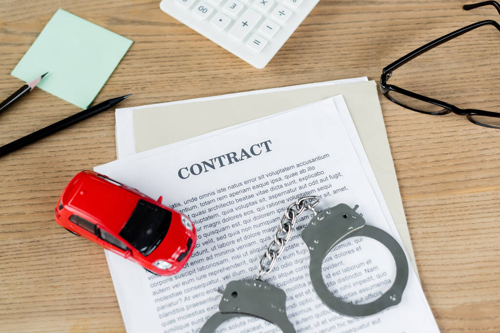 вид на игрушечный автомобиль по контракту рядом с наручниками и стаканами на столе - Фото, изображение