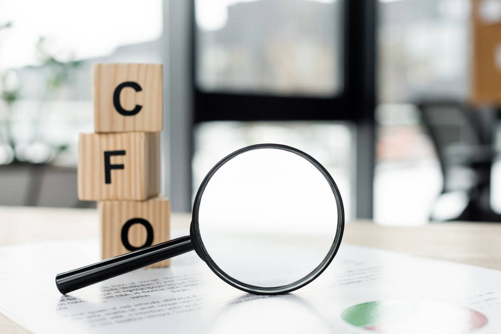 magnifying glass near cubes with cfo letters and document on desk - Photo, Image