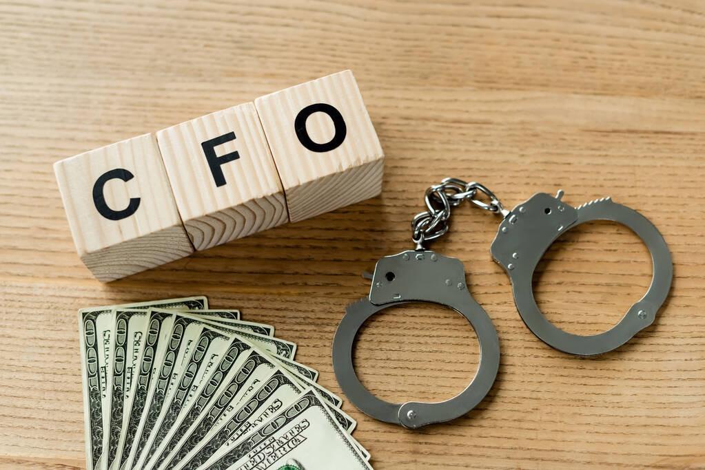 вид зверху на дерев'яні кубики з літерами cfo біля наручників і грошей на столі
 - Фото, зображення