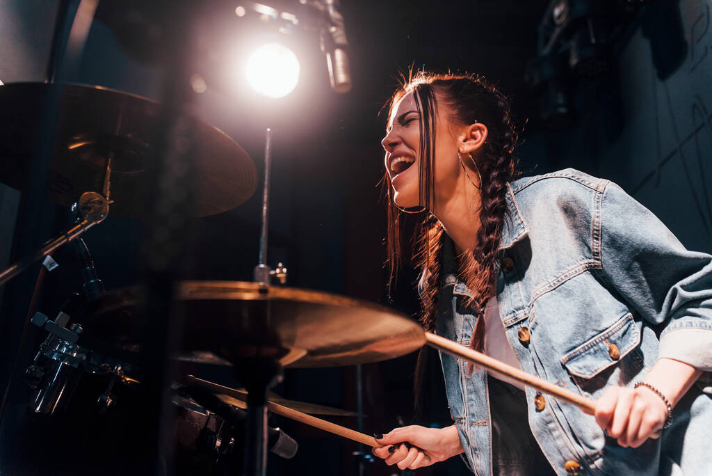 Plays drums. Young beautiful female performer rehearsing in a recording studio. - Foto, Bild