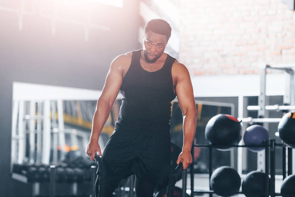 Sterke Afro-Amerikaanse man in sportieve kleding hebben workout dag in de sportschool. Cross-fit doen met behulp van touwen. - Foto, afbeelding