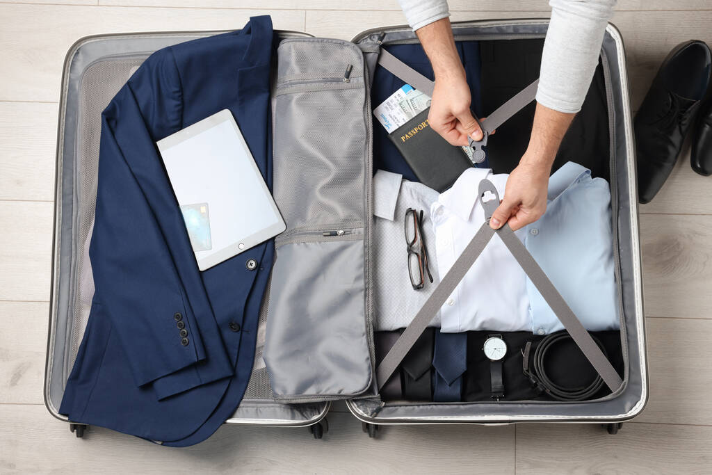 Mann packt Koffer für Geschäftsreise auf Holzboden, Draufsicht - Foto, Bild