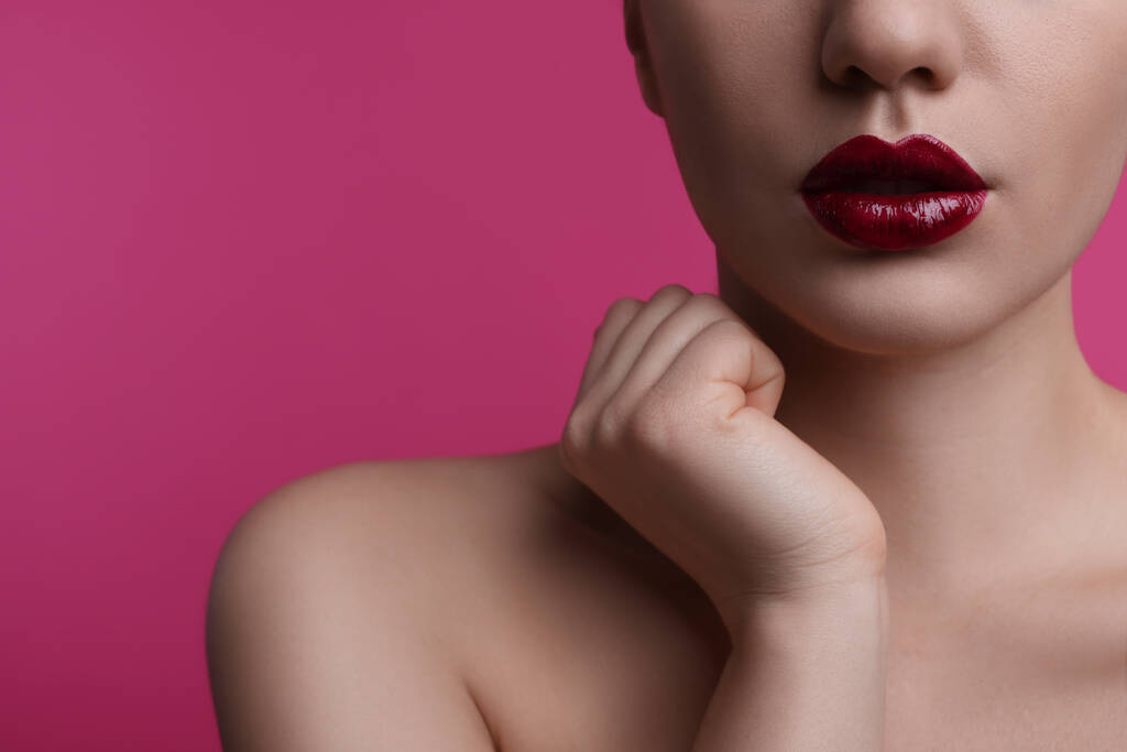 Vista de cerca de la mujer con hermosos labios llenos sobre fondo rosa, espacio para el texto - Foto, Imagen