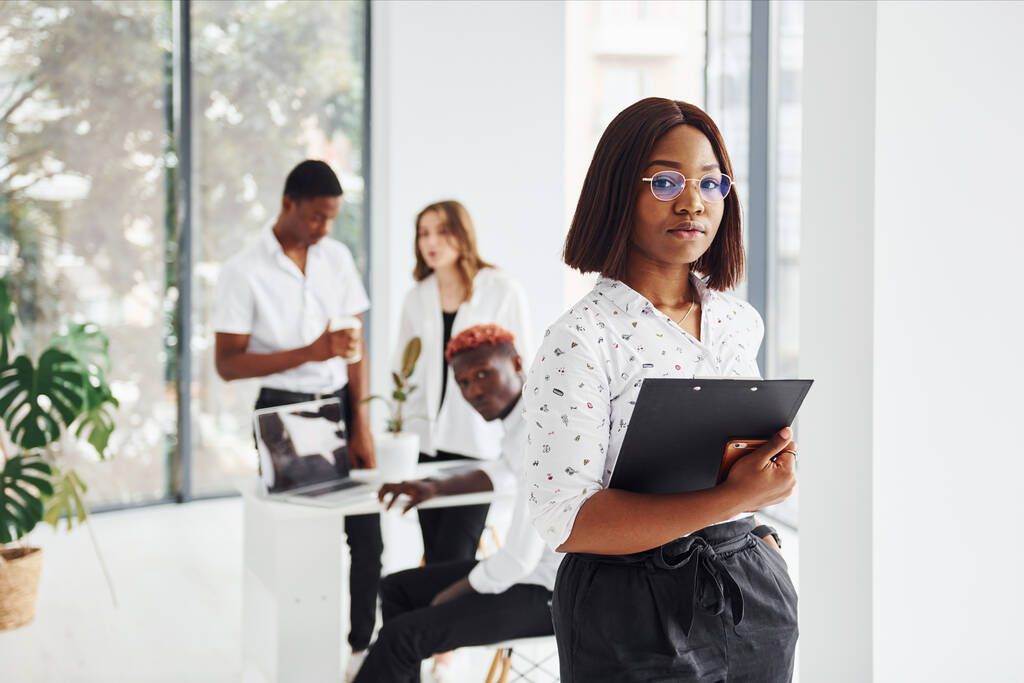 Belle femme en lunettes devant ses collègues. Groupe de gens d'affaires afro-américains travaillant ensemble au bureau. - Photo, image