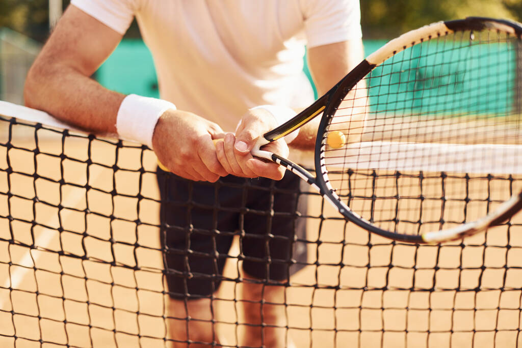 Γκρο πλαν άποψη του ηλικιωμένου άνδρα σε λευκό πουκάμισο και μαύρο σπορ σορτς που είναι στο γήπεδο τένις. - Φωτογραφία, εικόνα