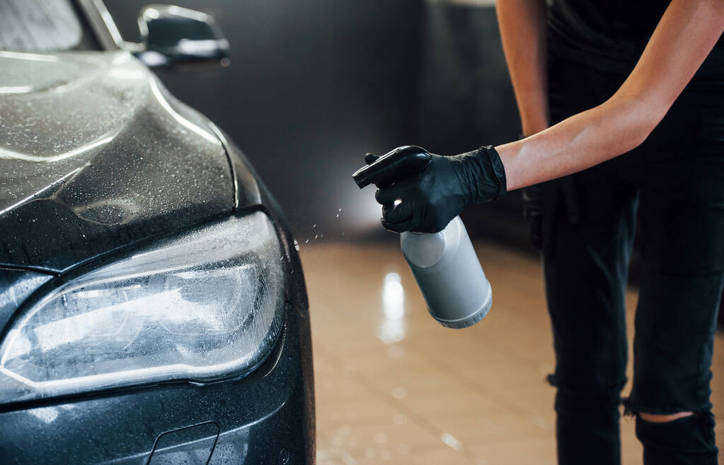 Spruzzando il veicolo. Moderna automobile nera ottenere pulito dalla donna all'interno della stazione di lavaggio auto. - Foto, immagini