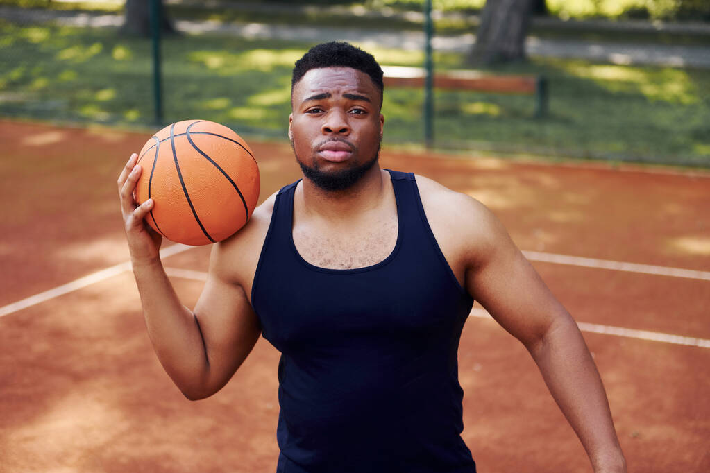 Αφροαμερικάνος στέκεται με μπάλα στο γήπεδο έξω. - Φωτογραφία, εικόνα