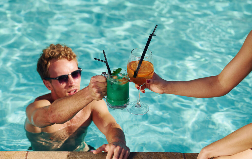 Hombre en gafas de sol animando cócteles con amigo en la piscina. - Foto, Imagen