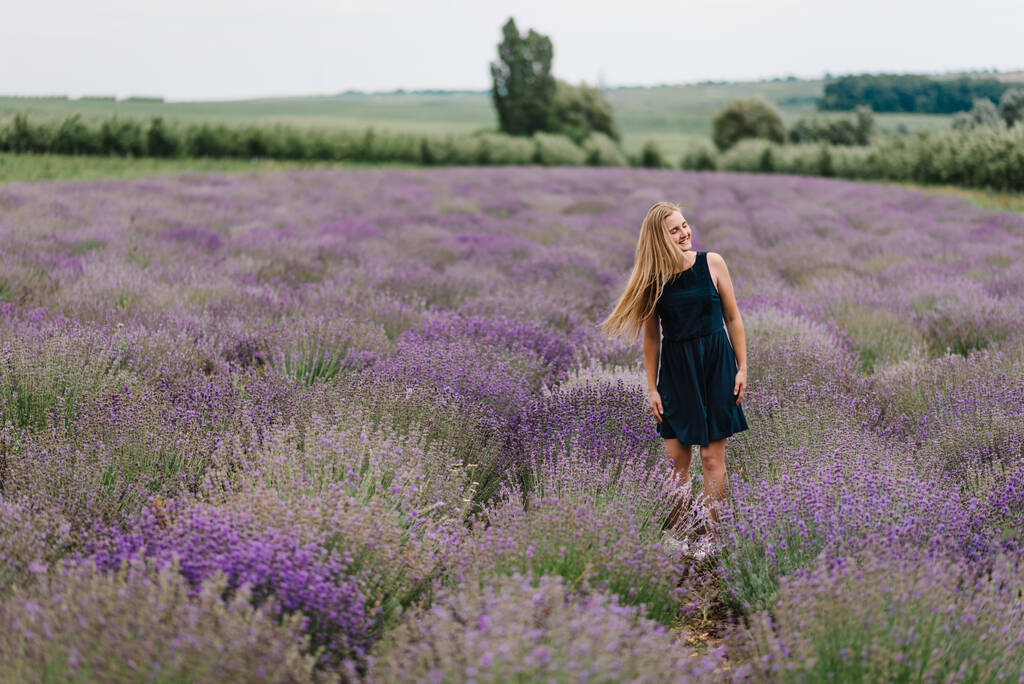Kaunis tyttö mekko seistä ja lentävät pitkät hiukset violetti laventeli alalla. Kaunis nainen hauska kävellä laventeli kentällä auringonlaskussa. Nauti kukka-aukiosta, kesäluonnosta. Kampaus. - Valokuva, kuva
