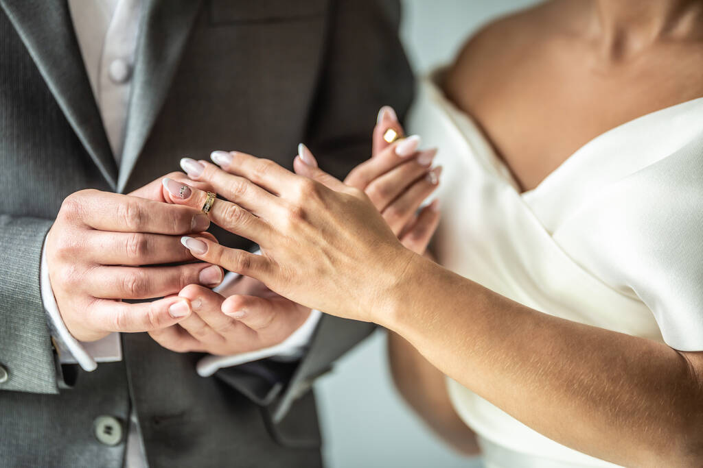 Les jeunes mariés échangent des bagues alors que le marié met une bague sur le doigt d'une mariée. - Photo, image