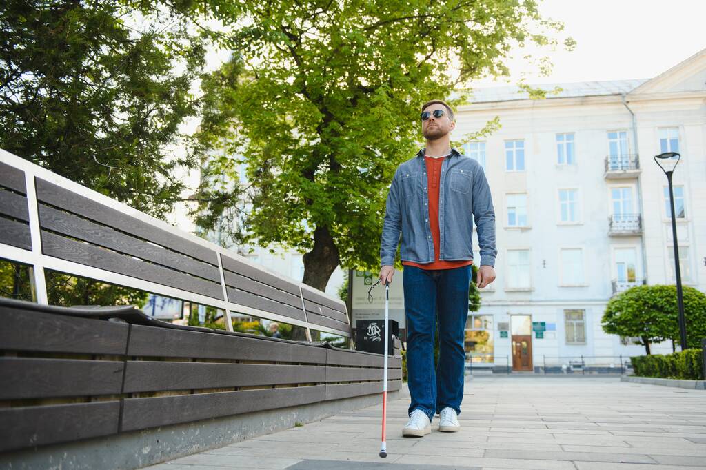 Joven ciego con bastón blanco caminando por la calle en la ciudad
. - Foto, Imagen