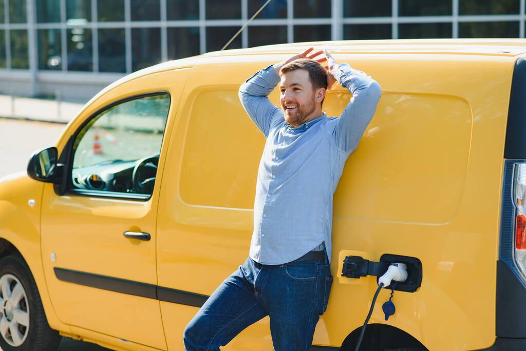 Ο άνθρωπος που φορτίζει το ηλεκτρικό του αυτοκίνητο στο σταθμό φόρτισης - Φωτογραφία, εικόνα