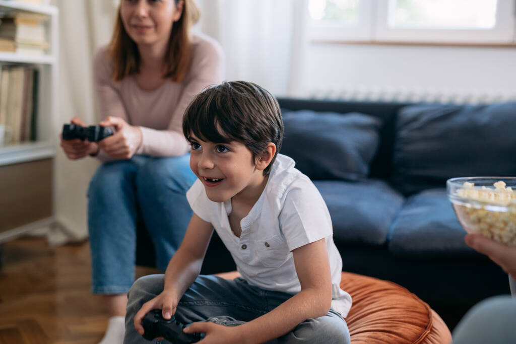 close up of young boy playing video games with his mother at home - Zdjęcie, obraz