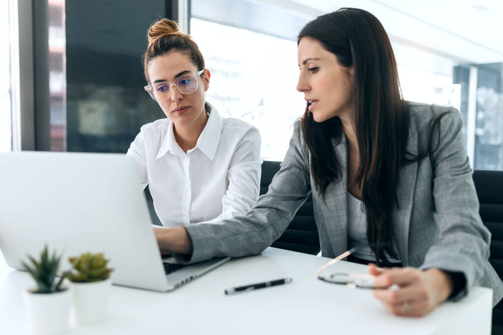 Fotografía de dos mujeres de negocios que trabajan juntas con el ordenador mientras hablan de trabajo en la oficina. - Foto, Imagen