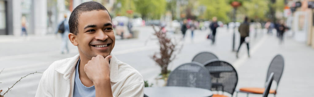 sonriente hombre afroamericano mirando en la terraza de la cafetería, pancarta - Foto, imagen