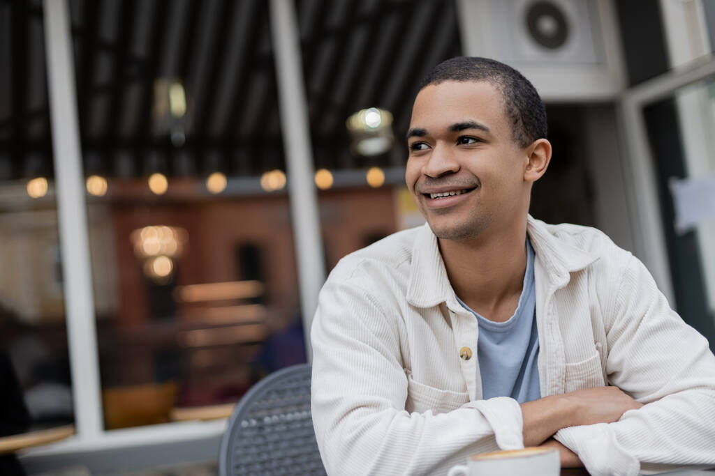 улыбающийся и молодой африканский американец смотрит на летнюю террасу - Фото, изображение