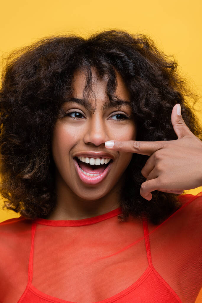 excitada afro-americana com cabelo encaracolado apontando com o dedo isolado no amarelo - Foto, Imagem