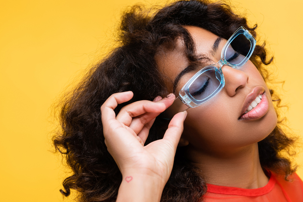 青いサングラスを黄色で隔てて目を閉じたアフリカ系アメリカ人女性 - 写真・画像